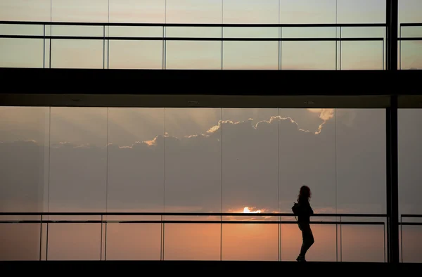 Vista silhueta de jovem empresária caminhando em prédio de escritórios moderno — Fotografia de Stock