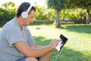 genç adam bir kulaklık ile müzik dinleme tablet pc ile rahatlatıcı