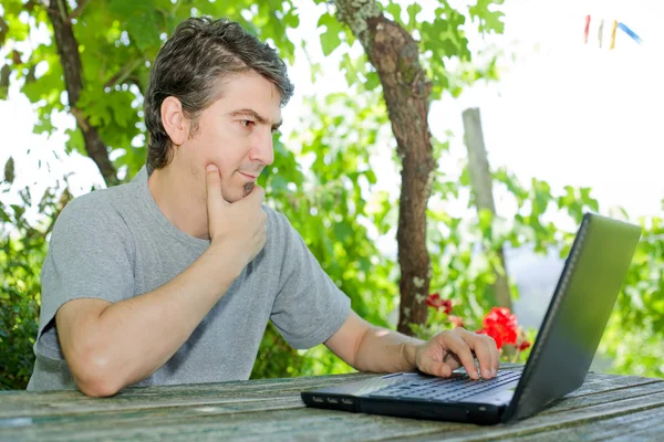 Mann sitzt draußen und arbeitet mit Laptop — Stockfoto