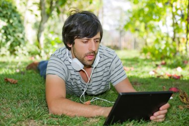 genç adam bir kulaklık ile müzik dinleme tablet pc ile rahatlatıcı