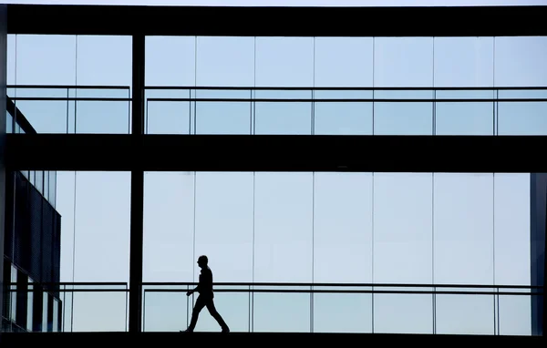 Vista de la silueta del joven empresario en un moderno edificio de oficinas interior —  Fotos de Stock