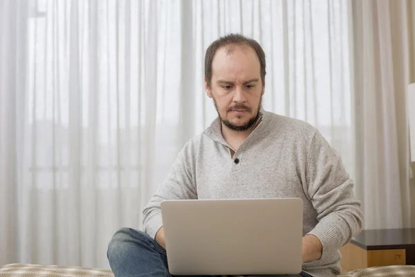 Man in bed werken met een laptop — Stockfoto