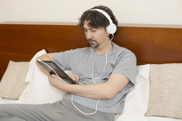 Casual man working with a tablet pc in bed — Stock Photo, Image