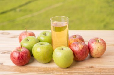 Elma ve elma suyu ahşap bir masada, açık havada.