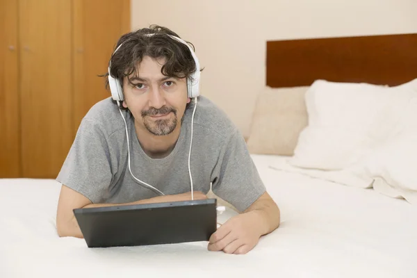 Hombre casual que trabaja con una tableta PC en la cama —  Fotos de Stock