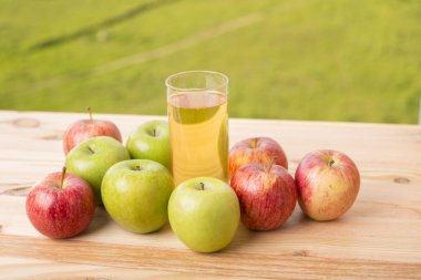 Elma ve elma suyu ahşap bir masada, açık havada.
