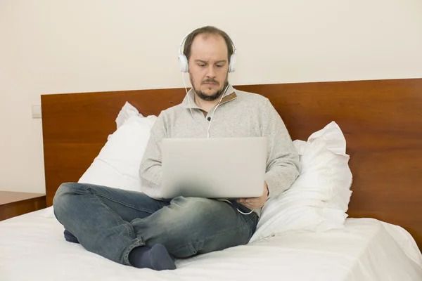 Человек в постели работает с ноутбуком — стоковое фото