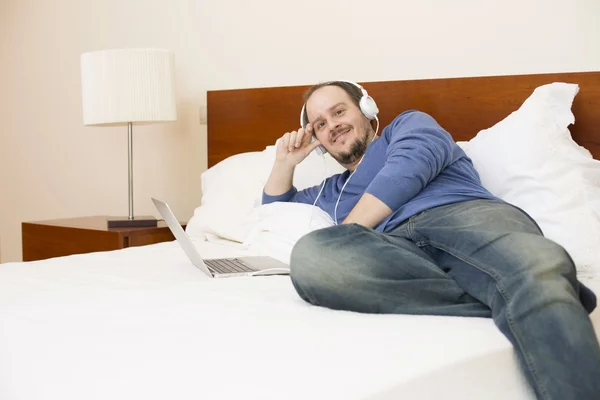 Uomo a letto che lavora con un computer portatile — Foto Stock