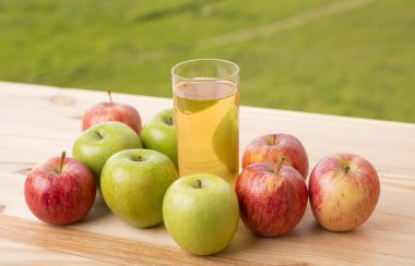 Elma ve elma suyu ahşap bir masada, açık havada.