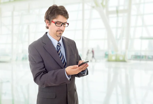 Jovem homem de negócios olhando preocupado com seu telefone, no escritório — Fotografia de Stock
