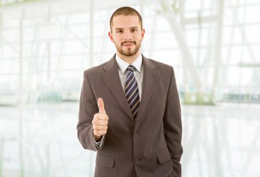 Genç iş adamı ofiste başparmağını kaldırıyor.