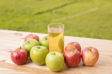Elma ve elma suyu ahşap bir masada, açık havada.