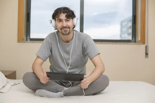 Uomo che utilizza un computer tablet mentre si trova in camera da letto — Foto Stock