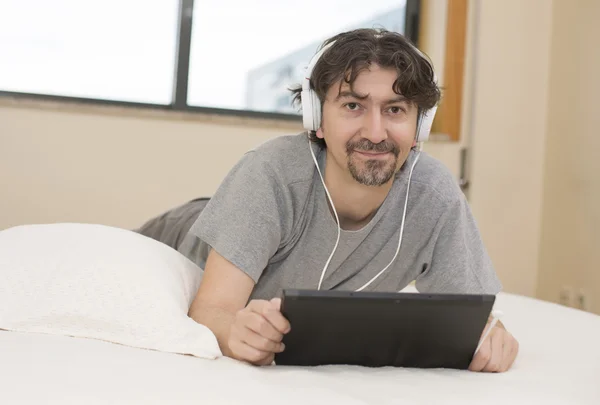 Casual man working with a tablet pc in bed — Stock Photo, Image