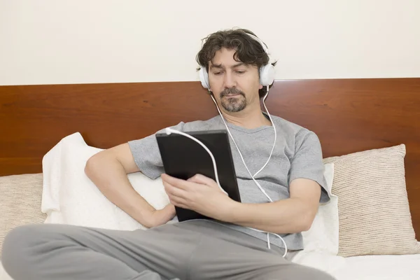 Uomo casuale che lavora con un tablet pc a letto — Foto Stock