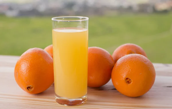 Verre de délicieux jus d'orange et d'oranges sur la table dans le jardin — Photo