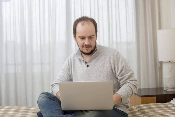 Uomo a letto che lavora con un computer portatile — Foto Stock