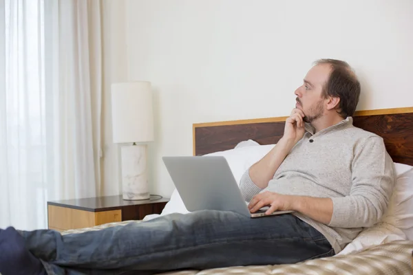 Adam yatakta bir dizüstü bilgisayar ile çalışma — Stok fotoğraf