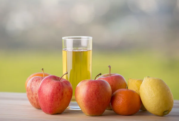 Buah-buahan dan jus apel di atas meja kayu, luar ruangan — Stok Foto