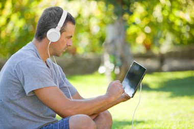 genç adam bir kulaklık ile müzik dinleme tablet pc ile rahatlatıcı