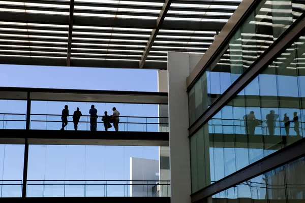 Bazı insanlar bir modern ofis binası iç görünümünü siluet — Stok fotoğraf