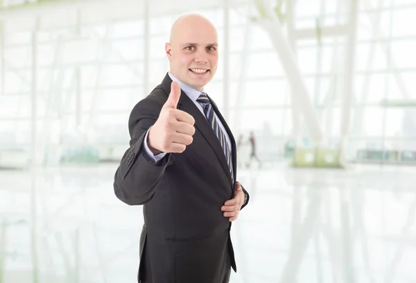 Молодой счастливый бизнесмен поднимает большой палец, в офисе — стоковое фото