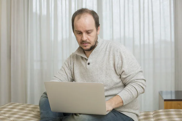 Uomo a letto che lavora con un computer portatile — Foto Stock