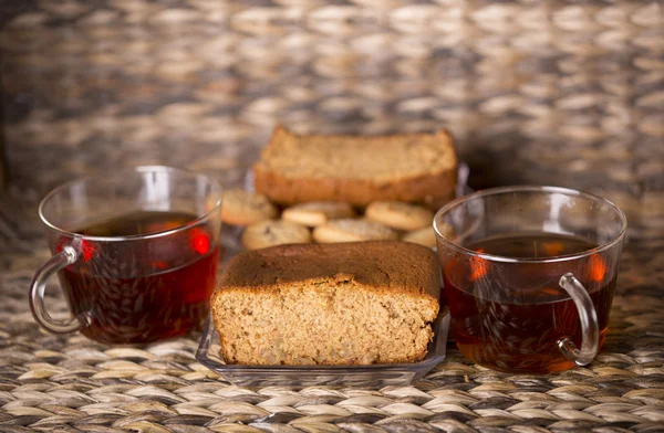 Thé, biscuits et gâteau sur une table en bois devant un fond en bois — Photo