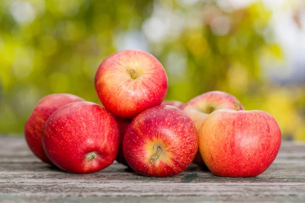 Manzanas sobre mesa de madera sobre fondo bokeh otoño — Foto de Stock