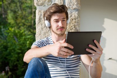 genç adam bir kulaklık ile müzik dinleme tablet pc ile rahatlatıcı