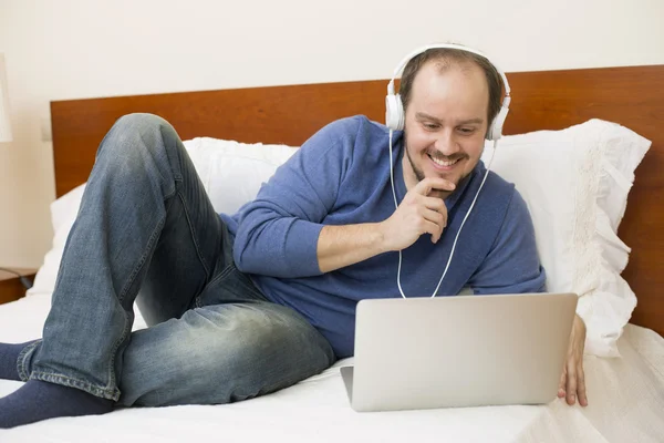 Homem na cama trabalhando com um laptop — Fotografia de Stock