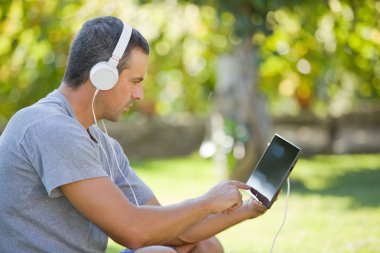 genç adam bir kulaklık ile müzik dinleme tablet pc ile rahatlatıcı