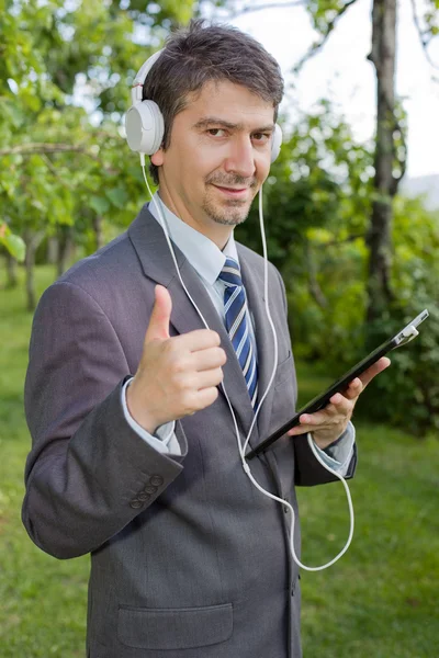 Homem de negócios feliz com tablet digital e fones de ouvido, ao ar livre — Fotografia de Stock