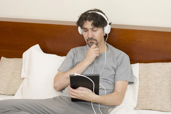 Casual man working with a tablet pc in bed — Stock Photo, Image