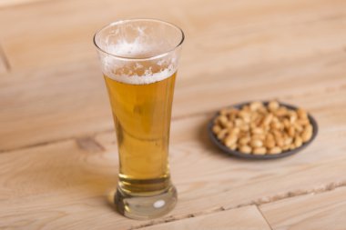 Ahşap masa, hareketsiz yaşam tarzı üzerinde kavrulmuş fıstık ile soğuk bira