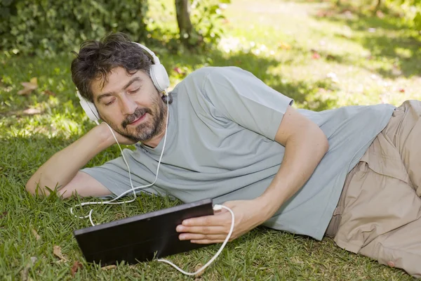 Young man holding a tablet with headphones, outdoor — Stock Photo, Image