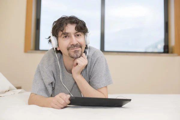 Hombre casual que trabaja con una tableta PC en la cama —  Fotos de Stock