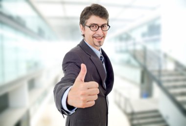 Genç iş adamı ofiste başparmağını kaldırıyor.