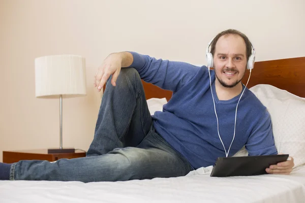 Příležitostné muž pracující s počítači tablet pc v posteli — Stock fotografie