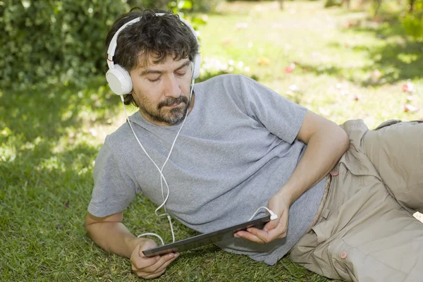 Young man holding a tablet with headphones, outdoor — Stock Photo, Image