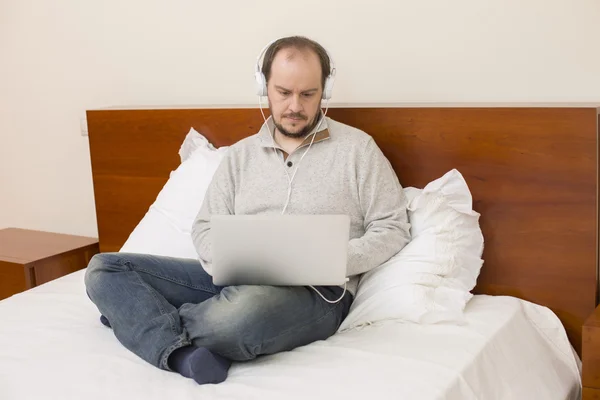 Mann im Bett arbeitet mit Laptop — Stockfoto