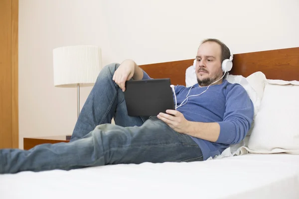 Příležitostné muž pracující s počítači tablet pc v posteli — Stock fotografie