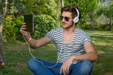 genç adam bir kulaklık ile müzik dinleme tablet pc ile rahatlatıcı
