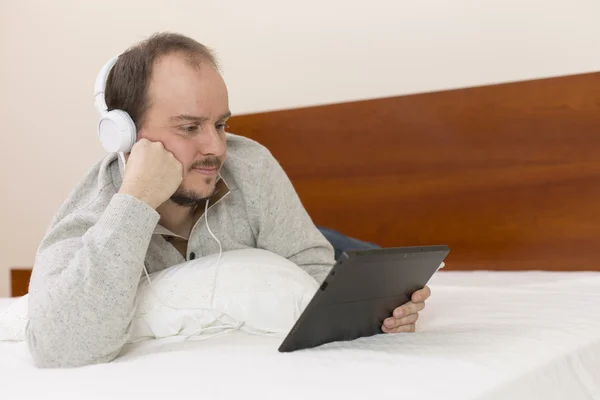 Uomo casuale che lavora con un tablet pc a letto — Foto Stock