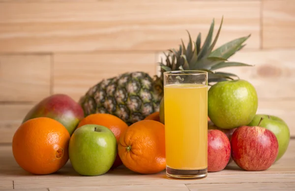 Mängd olika frukter och orange juice på ett träbord, studio bild — Stockfoto