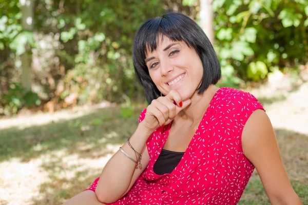 Giovane donna casual posa seduta, sorridente alla macchina fotografica, all'aperto — Foto Stock