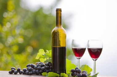 Tahta masada şarap şişesi ve üzüm.