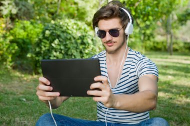 genç adam bir kulaklık ile müzik dinleme tablet pc ile rahatlatıcı