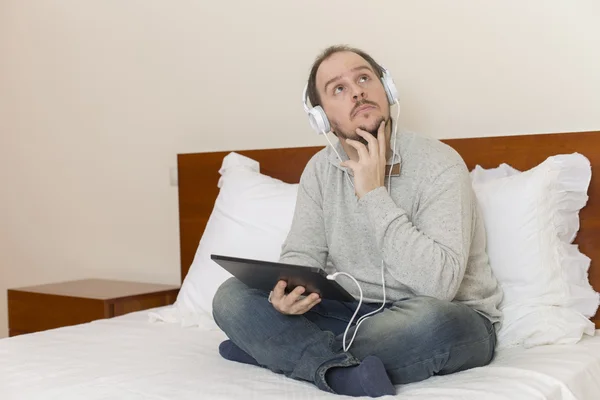 Homem casual trabalhando com um tablet pc na cama — Fotografia de Stock