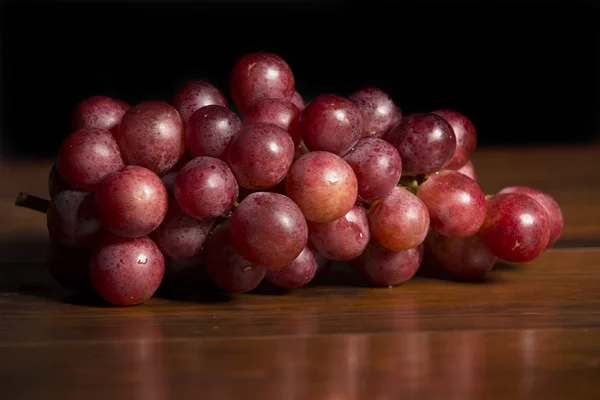 Un racimo de uvas rojas sobre fondo de madera — Foto de Stock